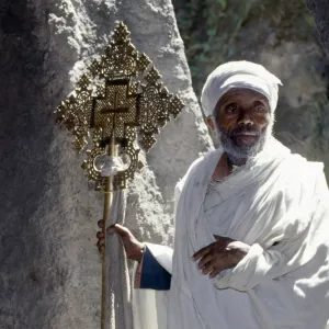 An old Ethiopian Orthodox priest holds a large brass