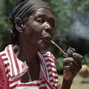 An old Luo lady smoking a traditional clay pipe