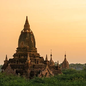 Old pagoda amidst trees against orange sky during sunrise, Bagan, Mandalay Region