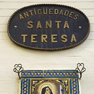 A painted ceramic mural depicting Santa Teresa praying before a cross