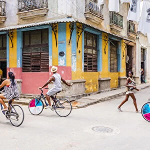 People cycling in a street in La Habana Vieja (Old Town), Havana, Cuba