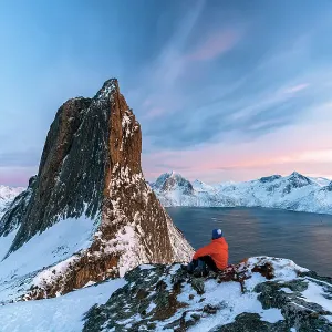 One person contemplating the sky at sunset sitting on a snowy ridge on Segla mountain, Senja, Troms county, Norway One person contemplating the sky at sunset sitting on a snowy ridge on Segla mountain, Senja, Troms county, Norway