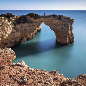 Person on Natural Sea Arch, Praia da Albandeira, Algarve, Portugal