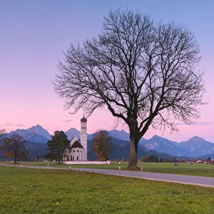 Pink sunrise on St Coloman Church surrounded by woods Schwangau Bavaria Germany Europe