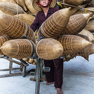 A portrait of a man on the bicycle loaded with the conical bamboo fish traps, near Hanoi