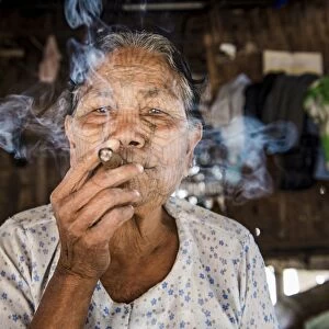 Rakhine state, Myanmar. Chin woman with traditional tattooed face smoking