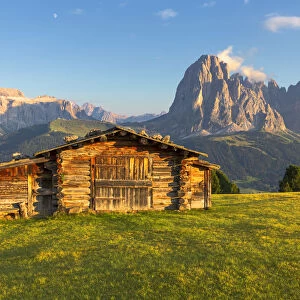 Last rays of sun on traditional hut with view on Sassolungo and Sella Group