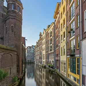 Residential buildings and houses amidst Oudezijds Achterburgwal canal against sky, De Wallen, Amsterdam, Netherlands