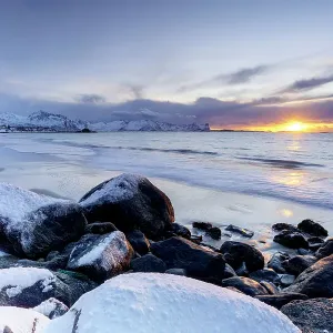 Romantic sky at sunset over the cold arctic sea washing the frozen Bovaer beach, Skaland, Senja, Troms county, Norway Romantic sky at sunset over the cold arctic sea washing the frozen Bovaer beach, Skaland, Senja, Troms county, Norway