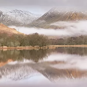 The ruins of Kilchurn Castle reflected in Loch Awe at dawn on a misty morning in the Scottish Highlands, Argyll and Bute, Scotland. Winter (March) 2017