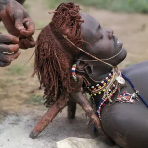 A Samburu warrior has his Ochred hair braided by a friend