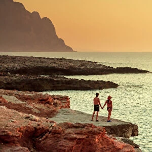 San Vito lo Capo, Sicily. A couple enjoying the sunset on the rock formations along the