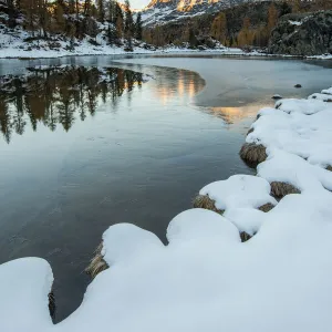 Sasso Moro peak at dawn reflects itself on the iced waters of Mufule Lake. Valmalenco