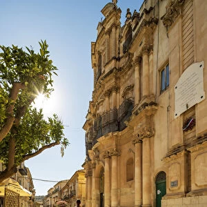 Scicli, Sicily. A woman walking in front of San Giovanni Evangelista church on a sunny