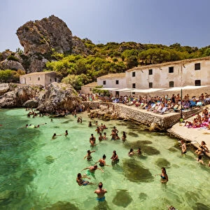 Scopello, Sicily. People taking a bath and sunbathing near the old tonnara