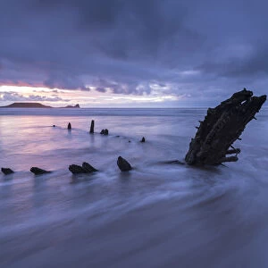Shipwreck of the Helvetia on Rhossili Beach, looking towards Worms Head at sunset