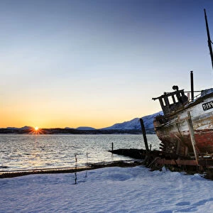 Shipwreck on the shore of Tromso fiord at sunrise, troms, norway