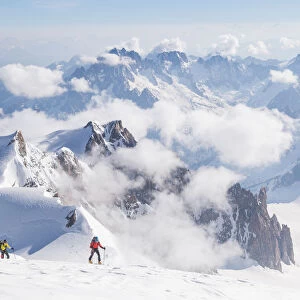 Ski mountaneers on the top of Mount Blanc with peaks in background