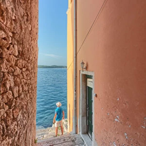 small arched opening overlooking the sea along the streets of Rovinj, tourist admires