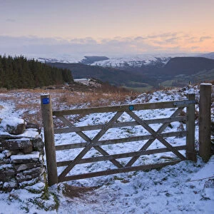 Snow covered gate and hilltop footpath on Allt yr Esgair with views to the Brecon Beacons mountains, Brecon Beacons National Park, Powys, Wales, UK. Winter (January) 2010