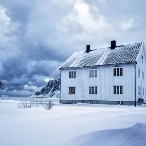 A solitary house at dusk in the snow capped village of Flakstad. Lofoten islands. Norway