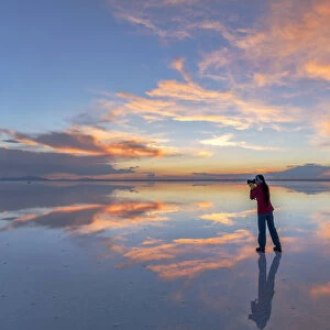 South America, Andes, Altiplano, Bolivia, Salar de Uyuni, woman taking pictures at sunset