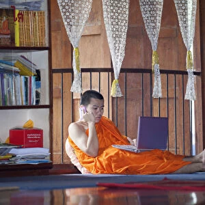 South East Asia, Thailand, Buddhist monk using a lap top and a mobile phone