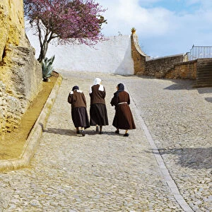 Spain, Andalucia, Malaga Province, Ronda, Three nuns walking up cobbled street