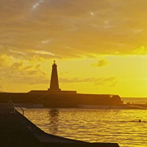 Spain, Canary Islands, Tenerife, Bajamar, Swimming pool and lighthouse during the sunset