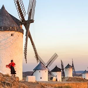 Spain, Castilea'La Mancha, Consuegra. Windmills at sunrise, with woman in spanish