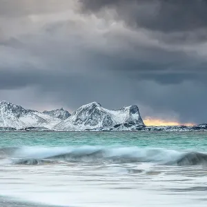 Storm clouds at sunset over snowcapped mountains and cold arctic sea, Bovaer beach, Skaland, Senja, Troms county, Norway Storm clouds at sunset over snowcapped mountains and cold arctic sea, Bovaer beach, Skaland, Senja, Troms county, Norway