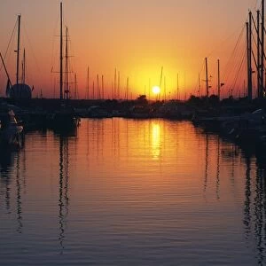 The sun sets over the yachts and pleasure boats in the marina