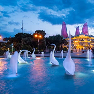 A swans fountain in the Baki Bulvari with Flame Towers in the background at twilight