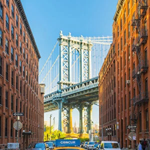 Taxi passing under the Manhattan bridge with the Empire state building framed in the