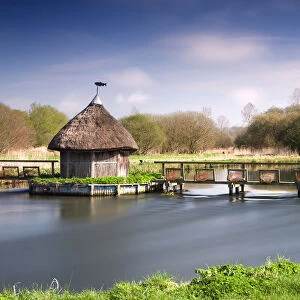 Thatched fishermans hut and eel traps spanning the River Test near Leckford