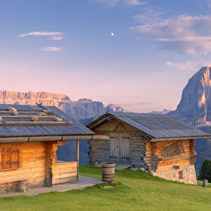 Traditional huts at sunset with Sassolungo and Sella Group in the background