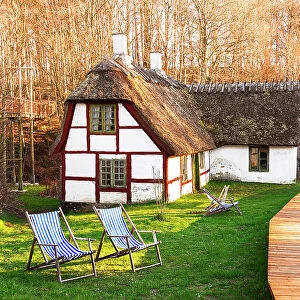 Traditional old danish farm house with thatched roof, green lawn and sun chairs in the zealand countryside, Zealand, Denmark, Europe
