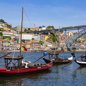 Traditional Rabelo boat designed to carry wine down Douro river with city skyline behind