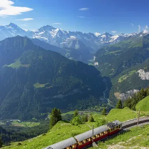 Train of cogwheel railway with Jungfrau and Monch mountains, Schynige Platte, Jungfrau Region, Bernese Oberland, Switzerland Train of cogwheel railway with Jungfrau and Monch mountains, Schynige Platte, Jungfrau Region, Bernese Oberland, Switzerland