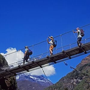 Trekkers crossing a suspension bridge over the Dudh Kosi river