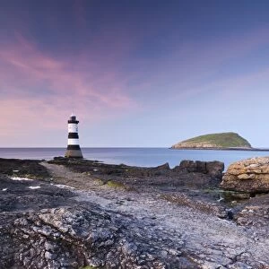 Twilight on the rocky Anglesey coast looking towards Penmon Point Lighthouse and Puffin Island