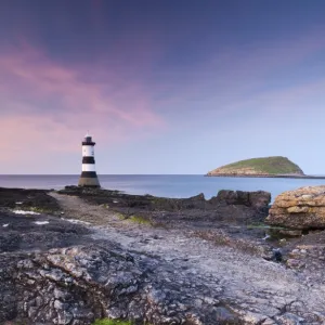 Twilight on the rocky Anglesey coast looking towards Penmon Point Lighthouse and Puffin Island