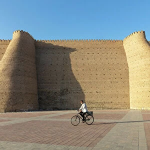 Uzbekistan, Bukhara, UNESCO world heritage site, Ark Fortress, a man cycles past the city walls