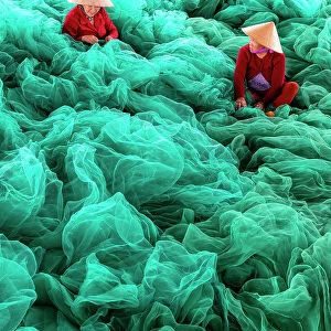 Vietnam, Cam Ranh, women mend green fishing nets