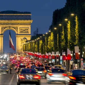 View down the Champs Elysees to the Arc de Triomphe, illuminated at dusk, Paris, France