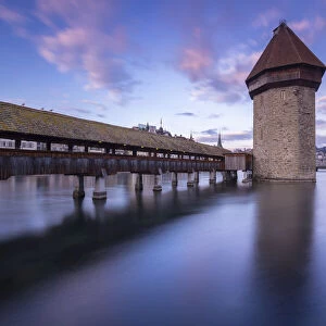 View of the Kapellbrucke bridge and the Wasserturm at sunset reflected on the Reuss river. Lucerne, canton of Lucerne, Switzerland