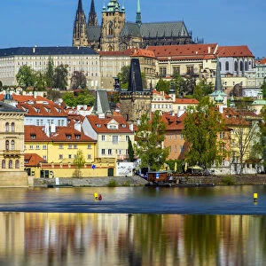 View of Mala Strana district with St. Vitus cathedral reflected in the Vltava River