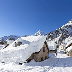 View of mountain huts and the church of the small town of Crampiolo in winter