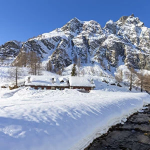 View of mountain huts near the torrent Devero in the small town of Crampiolo in winter