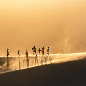 Walvis Bay, Namibia, Africa. People walking on the edge of a sand dune at sunset